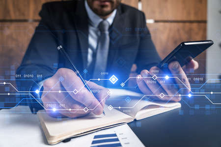 A businessman in office taking notes using phone and technology hologram. Multiexposure. Formal wear.の写真素材