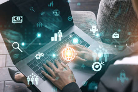 Businesswoman typing on computer in office. Financial and research icon hologram. Double exposure.