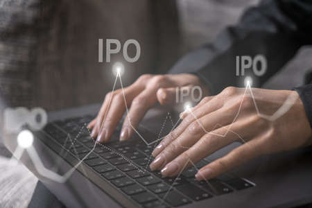 Businesswoman typing on computer in office. IPO icon hologram. Double exposure.の写真素材