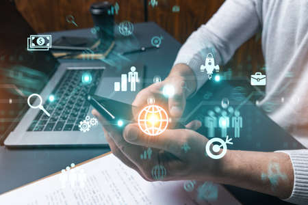 Man using phone. Hands typing smartphone. Double exposure with business icons hologram. Close up....