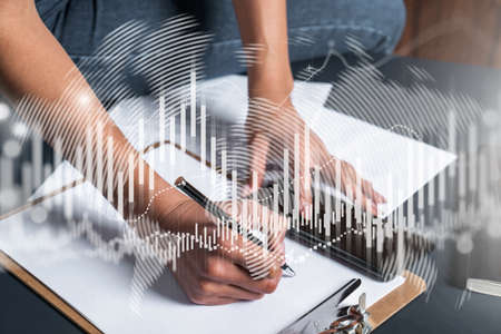 Businesswoman taking notes using smart-phone. Financial forex graph and chart hologram double...