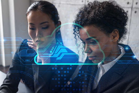 Two businesswomen work together in modern office on new project. Double exposure. Concept of success. Cloud hologram.の写真素材