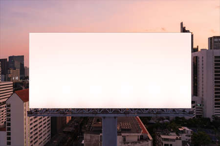 Blank white road billboard with Bangkok cityscape background at night time. Street advertising poster, mock up, 3D rendering. Front view. The concept of marketing communication to promote idea.の写真素材