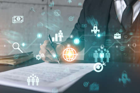 Businessman in suit signs contract. Double exposure with business icons hologram. Man signing...