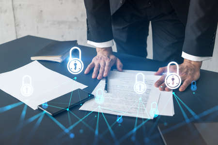 Businessman in suit signs contract. Double exposure with lock icon hologram. Man signing agreement on company data security. Safety concept.の写真素材