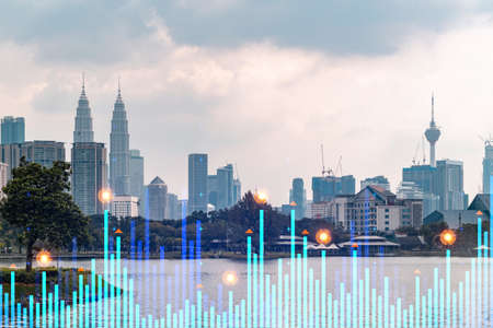 Market behavior graph hologram, sunset panoramic city view of Kuala Lumpur. KL is popular location to achieve financial degree in Malaysia, Asia. The concept of financial data analysis.の写真素材