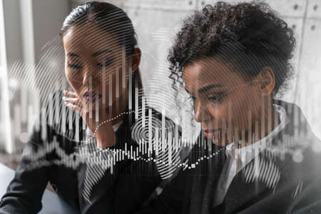 Two businesswomen work together in modern office on new project. Double exposure. Concept of success. Forex stock market graph.の写真素材