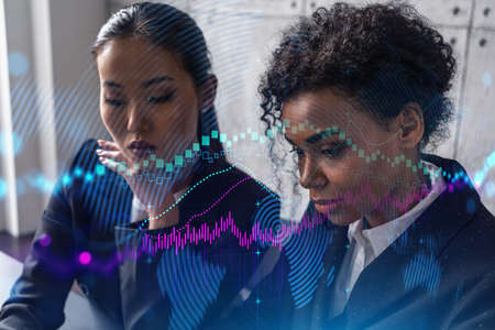 Two businesswomen work together in modern office on new project. Double exposure. Concept of success. Forex stock market graph.の写真素材