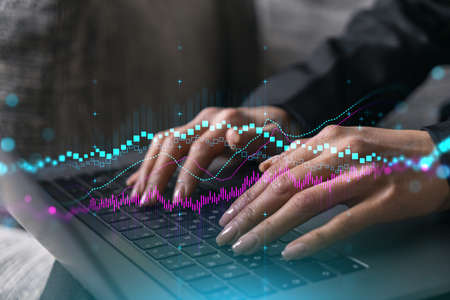 Businesswoman typing on computer in office. Fiancial graph hologram. Double exposure.