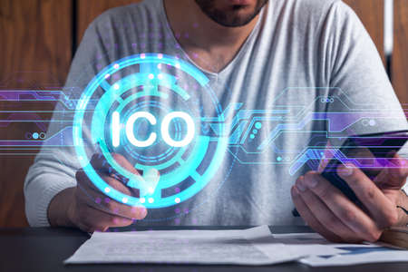Multiexposure of man signing contract with phone and ico hologram. Concept of initial coin offering,...