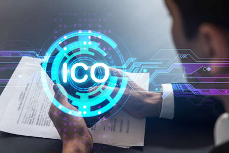 Analyst in office working with Smartphone, ICO hologram, typing phone. Double exposure.