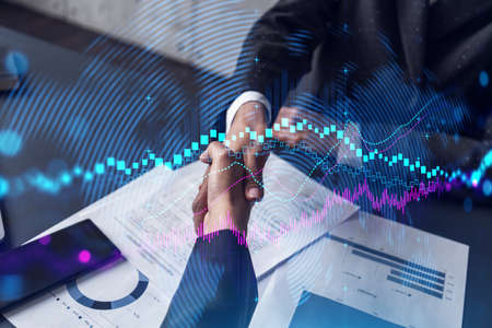 Double exposure of two businesspeople handshake and forex chart hologram drawing background. Concept...