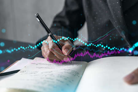 Financial stock market graph hologram and a woman taking notes. Business education and analysis...