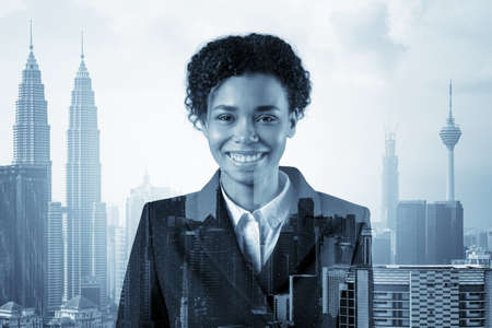 Successful smiling black African American business woman in suit. Kuala Lumpur cityscape. The concept of woman in business. KL skyscrapers. Double exposure.の写真素材
