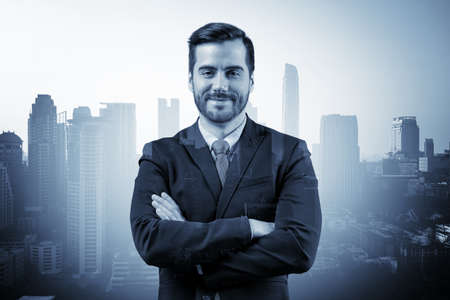 Prosperous European entrepreneur in suit in crossed arms pose. Bangkok cityscape. The concept of...