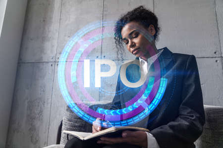 Businesswoman taking notes and IPO hologram. Double exposure. Business technology initial primary...