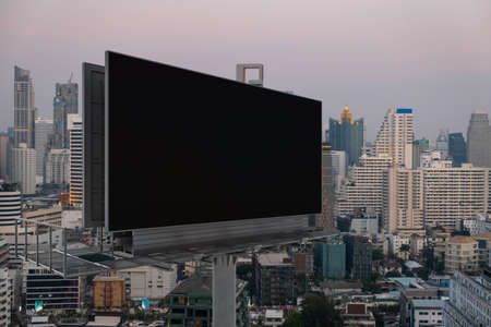Blank black road billboard with Bangkok cityscape background at sunset. Street advertising poster, mock up, 3D rendering. Side view. The concept of marketing communication to promote or sell idea.の写真素材