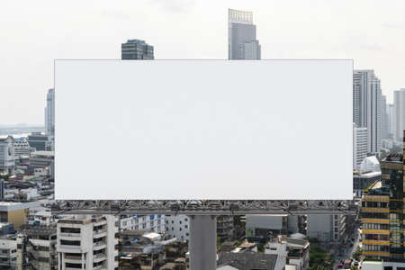 Blank white road billboard with Bangkok cityscape background at day time. Street advertising poster, mock up, 3D rendering. Front view. The concept of marketing communication to promote or sell idea.の写真素材