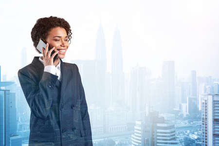 Successful smiling black African American business woman in suit pensively talking phone, Kuala...