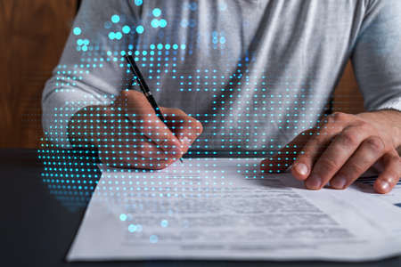 Double exposure of man signing contract and world map hologram. Concept of international business people connection.の写真素材