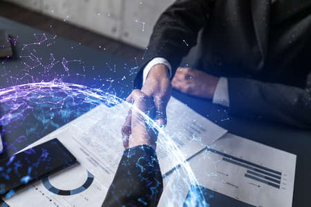 Double exposure of two businesspeople handshake and abstract technology hologram drawing background....