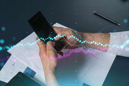 Man using phone. Hands typing smartphone. Double exposure with forex graph hologram. Close up....