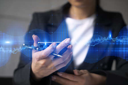 Businesswoman using smart phone in office. Forex chart hologram. On-line trading stock market concept. Double exposure.の写真素材