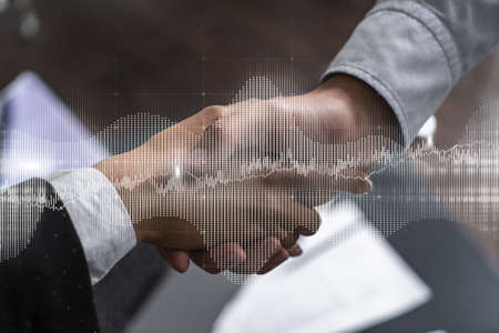 Double exposure of two businesspeople handshake and forex chart hologram drawing background. Concept...