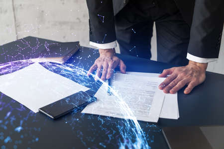 Businessman in suit signs contract. Double exposure with abstract technology hologram. Man signing...