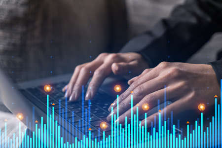 Businesswoman typing on computer in office. Fiancial graph hologram. Double exposure.の写真素材