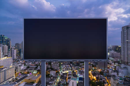 Blank black road billboard with Bangkok cityscape background at night time. Street advertising...