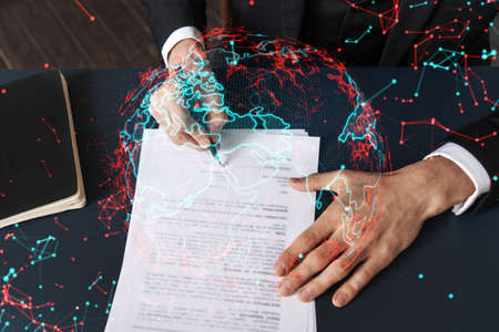 Businessman in suit signs contract. Double exposure with world map hologram. Man signing agreement...