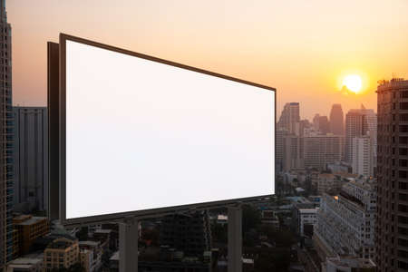 Blank white road billboard with Bangkok cityscape background at sunset. Street advertising poster, mock up, 3D rendering. Side view. The concept of marketing communication to promote or sell idea.の写真素材
