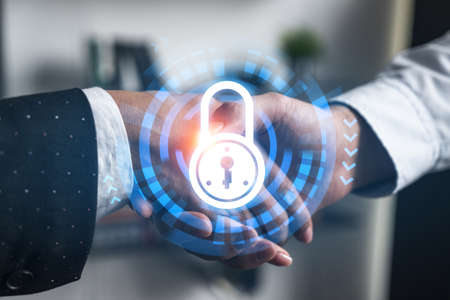 Multiexposure of two businesspeople handshake and lock icon hologram drawing background. Concept of internet business security information data. Formal wear.の写真素材