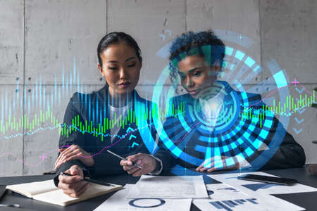 Two businesswomen work together in modern office on new project. Double exposure. Concept of success. Financial graph.の写真素材