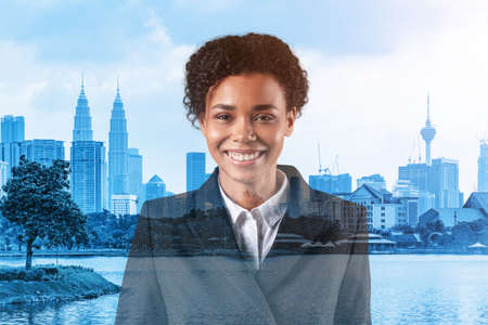 Successful smiling black African American business woman in suit. Kuala Lumpur cityscape. The concept of woman in business. KL skyscrapers. Double exposure.の写真素材