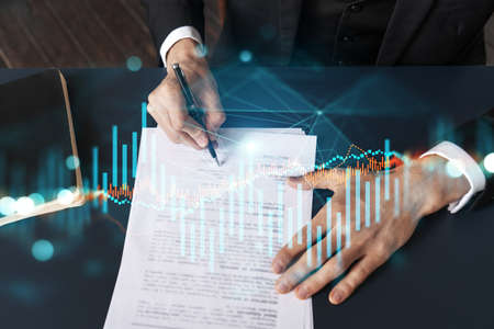 Businessman in suit signs contract. Double exposure with forex graph hologram. Man signing brokerage...