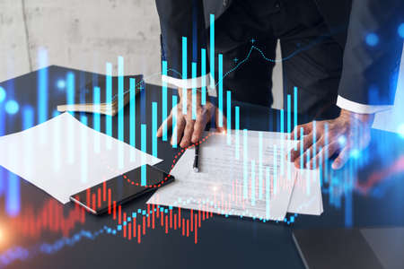 Businessman in suit signs contract. Double exposure with forex graph hologram. Man signing brokerage...