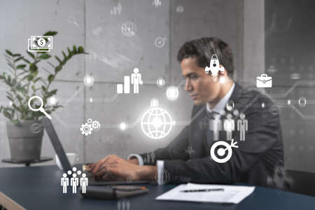 Businessman in office working with laptop, develop fintech approach to business, typing computer assemble data for new opportunities. Double exposure.の写真素材