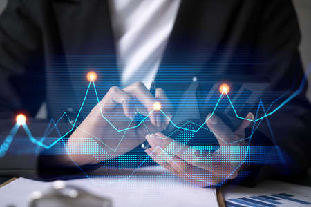 Businesswoman using smart phone in office. Financial chart hologram. Stock market analysis concept....