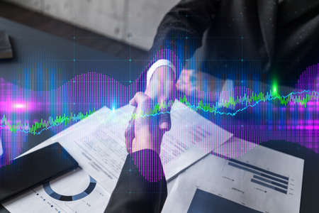 Double exposure of two businesspeople handshake and forex chart hologram drawing background. Concept...