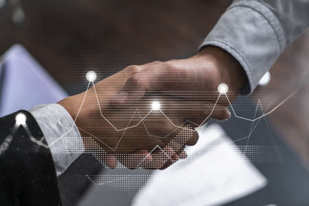 Double exposure of two businesspeople handshake and financial chart hologram drawing background. Concept of partnership in business and data analysis. Formal wear.の写真素材