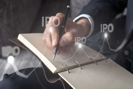 Businessman in suit taking notes. Multiexposure with ipo symbol hologram. Man writing down important information in his business diary. Investment concept.の写真素材