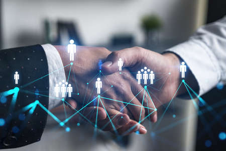 Double exposure of two businesspeople handshake and social media network icon hologram drawing...