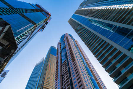 Low angle shot of steel and glass skyscrapers of busy downtown of Dubai, UAE at a sunny day. Modern low-angle view of the capital of the Emirate of Dubai. A business and finance hub of Western Asia.の写真素材