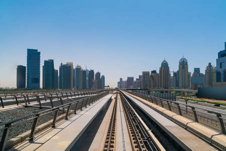 The way towards skyscrapers of financial downtown of Dubai by modern futuristic train. Tech railway delivers commuters to the financial downtown of Dubai. International business hub.の写真素材