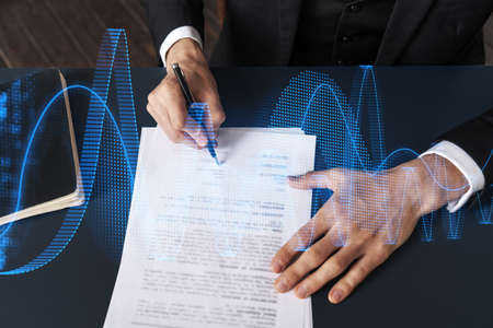 Businessman in suit signs contract. Double exposure with financial chart hologram. Man signing mortgage agreement. Real estate market analysis and investment concept.の写真素材