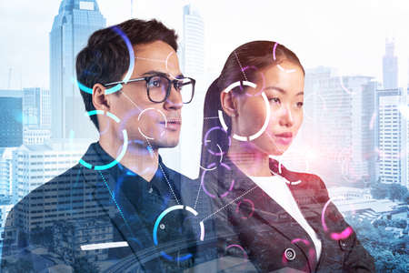 Businessman and businesswoman as a part of corporate team pondering about technology as a business necessity for tremendous growth in commerce. Tech hologram icons over Kuala Lumpur background.の写真素材