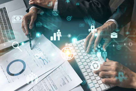 Two business people working together on research and analysis of project. Blue icon infographic hologram. Double exposure.の写真素材