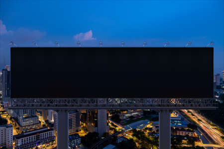 Blank black road billboard with Kuala Lumpur cityscape background at night time. Street advertising...